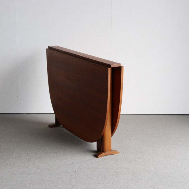 Mid-century British vintage teak folding dining table with rich wood grain and simple tapered legs in closed position.