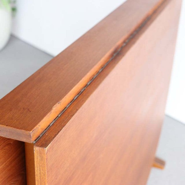Vintage teak folding dining table edge showing warm wood grain and clean mid-century British design details.
