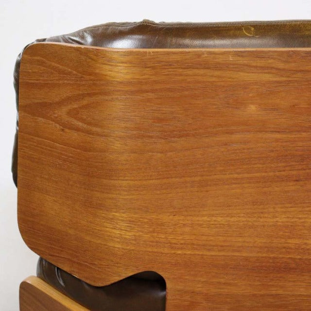 Mid-century teak armrest with smooth wood grain and rounded edges on British vintage leather sofa.