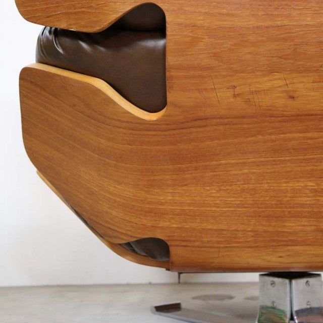 Close-up of mid-century British teak frame with smooth wood grain and curved edges on vintage leather sofa leg from Denmark.