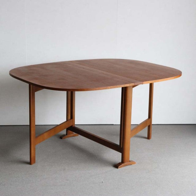 Vintage mid-century teak dining table with rounded rectangular top, British-Danish design, folding legs with cross brace.