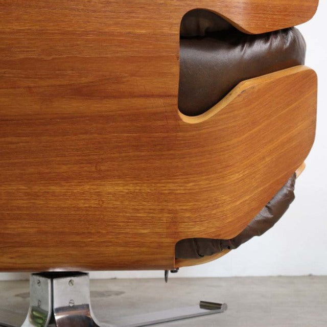 Mid-century British vintage teak armchair with curved wooden frame and dark leather upholstery showing wood grain and chrome .