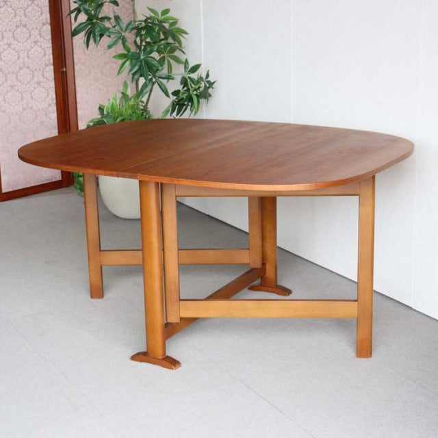 Vintage mid-century teak dining table with folding leaf, British-Denmark design, smooth wood grain, and sturdy square legs.