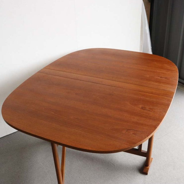 Mid-century vintage teak dining table with rounded edges, British-Denmark style, smooth wood grain surface, folding design,.