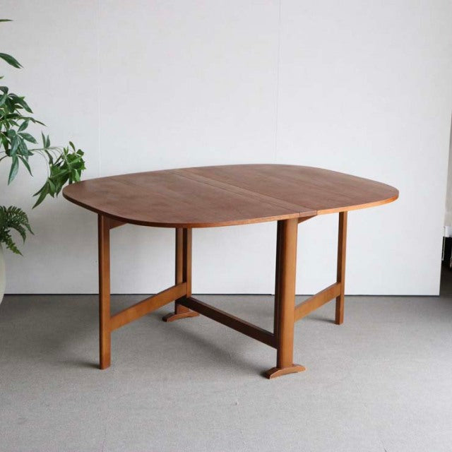 Mid-century vintage teak dining table with rounded edges, sturdy British-Denmark style legs, and rich wood grain finish.