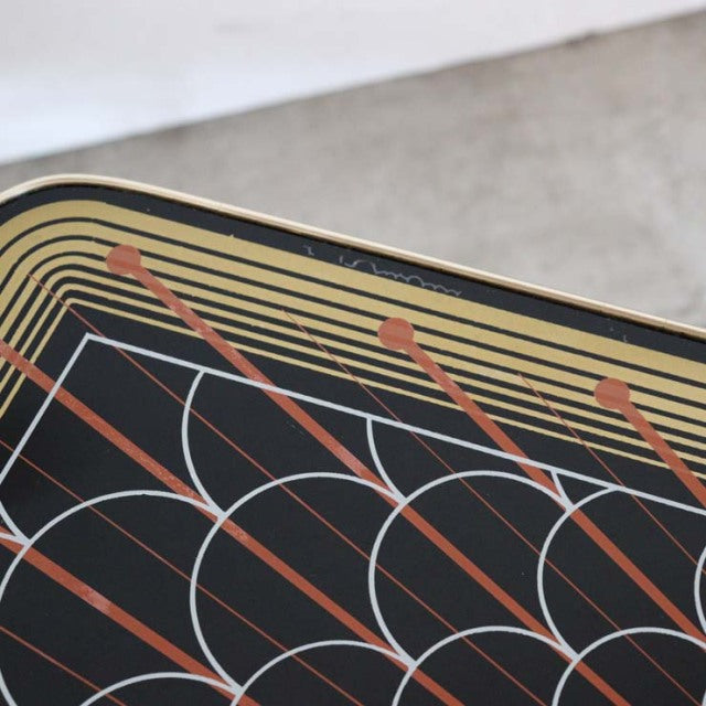 Mid-century British teak coffee table with geometric patterned top featuring black, beige, and rust colors and rounded edges.