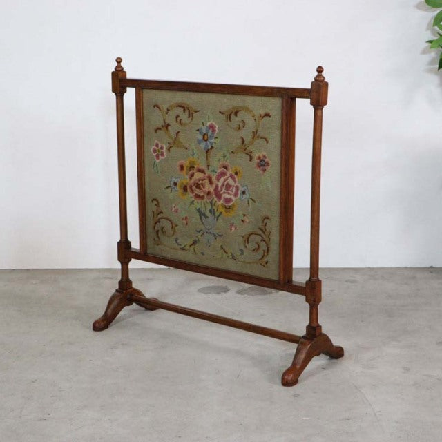 Vintage teak fire screen with mid-century British design, floral tapestry panel, turned finials, and sturdy carved legs.
