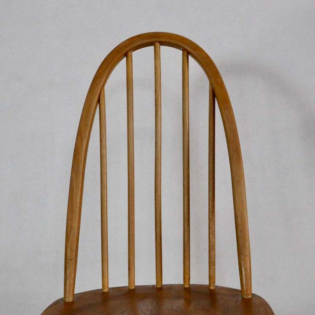 Vintage British mid-century teak Ercol Quaker chair with arched spindle back and smooth wooden seat.