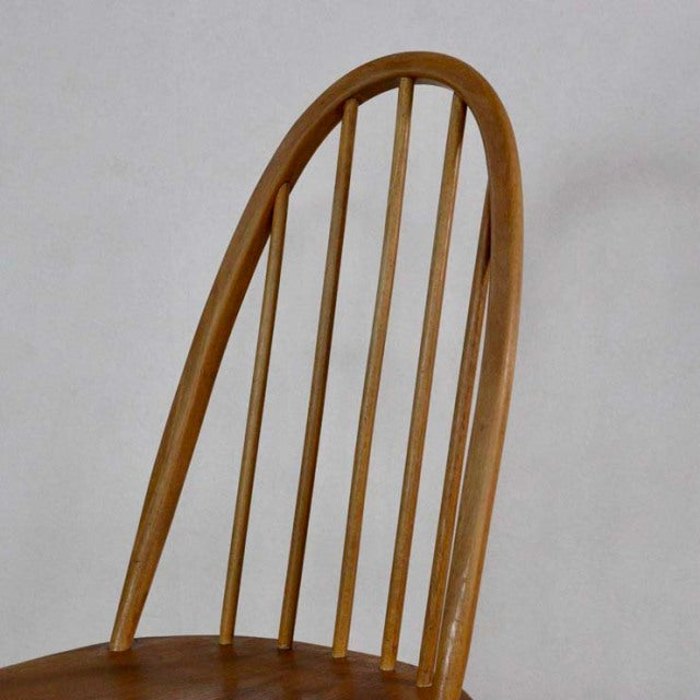 Vintage British mid-century Ercol Quaker chair in teak with curved arched back and slender spindle legs.