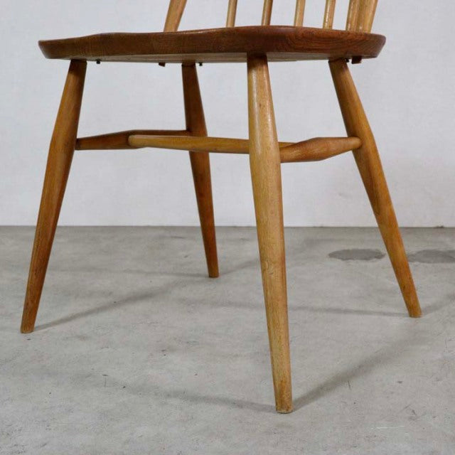 Mid-century British Ercol Quaker chair in vintage teak with turned and tapered legs and visible wood grain.