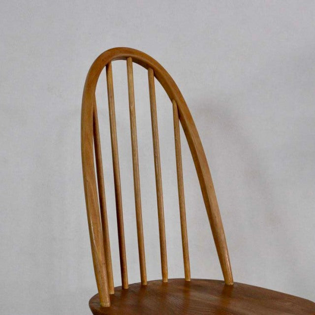 Vintage British Ercol Quaker chair in teak with tall arched spindle back and smooth wood grain, mid-century design.