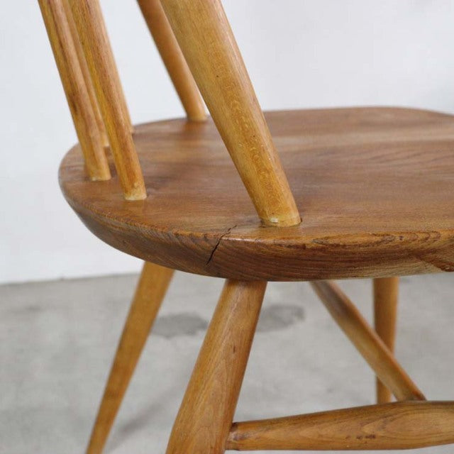 Close-up of vintage British mid-century teak Ercol Quaker chair leg and rounded seat with wood grain and smooth finish.