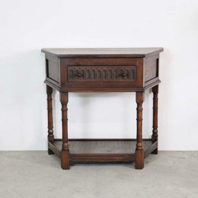 Mid-century British vintage teak bedside cabinet with carved drawer front, turned legs, and lower shelf.