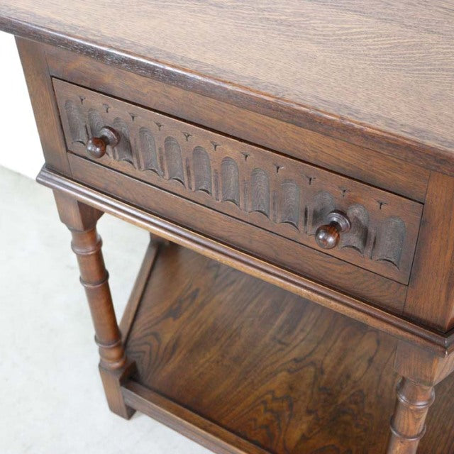 Vintage British mid-century teak bedside cabinet with carved drawer front and turned legs.
