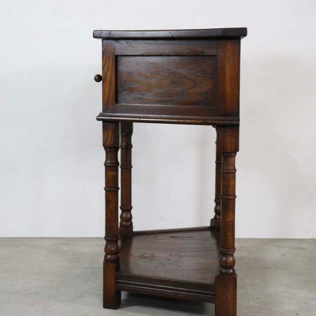 Mid-century British teak bedside cabinet with rich wood grain, turned legs, and lower shelf in vintage Denmark style.