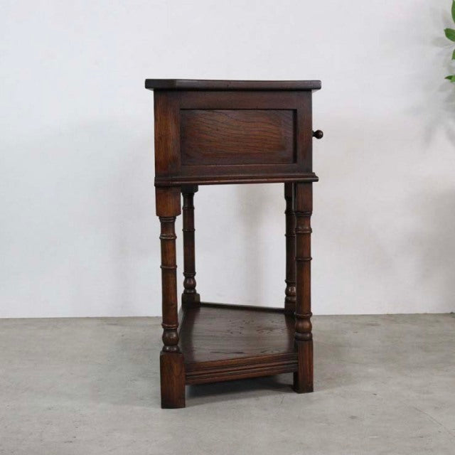 Vintage British mid-century teak bedside cabinet with paneled door, turned legs, and lower shelf.