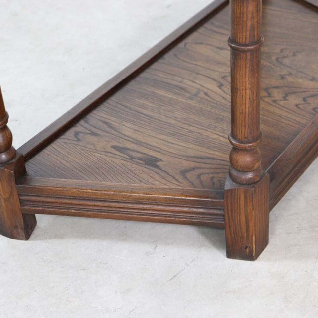 Close-up of British vintage oak bedside cabinet’s lower shelf showing rich oak grain, turned mid-century legs, and.