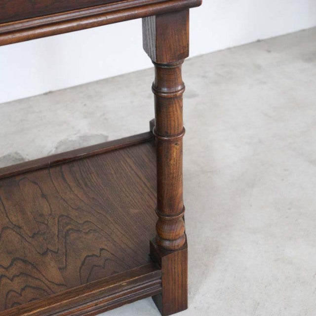 Mid-century British teak bedside cabinet corner with rich wood grain and turned leg detail.