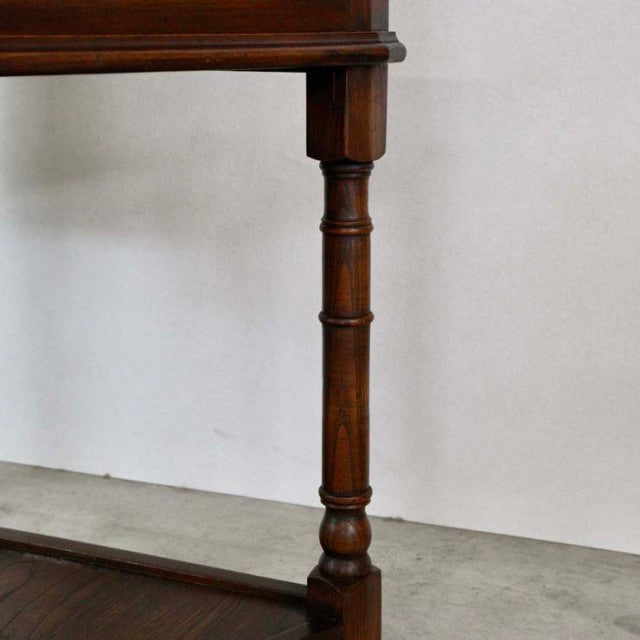 Mid-century British vintage teak hall table leg with rich wood grain and turned detailing against plain background.