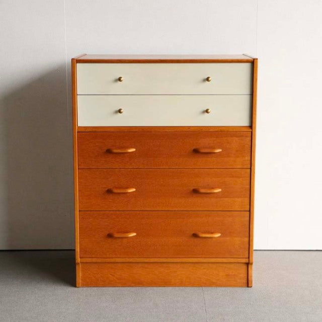 Mid-century British G-Plan teak chest with Chinese white top drawers, sleek wooden handles, and tapered legs.