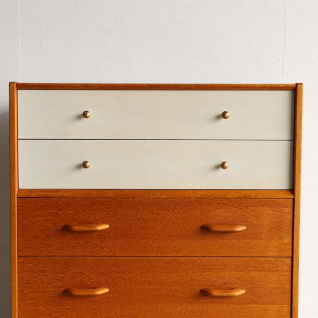 Mid-century British G-Plan teak chest with two white upper drawers and two lower teak drawers, rounded wooden handles, and.