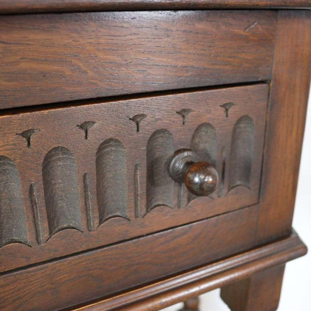 Vintage British mid-century teak bedside cabinet with carved arched detailing and round wooden knob on tapered legs.