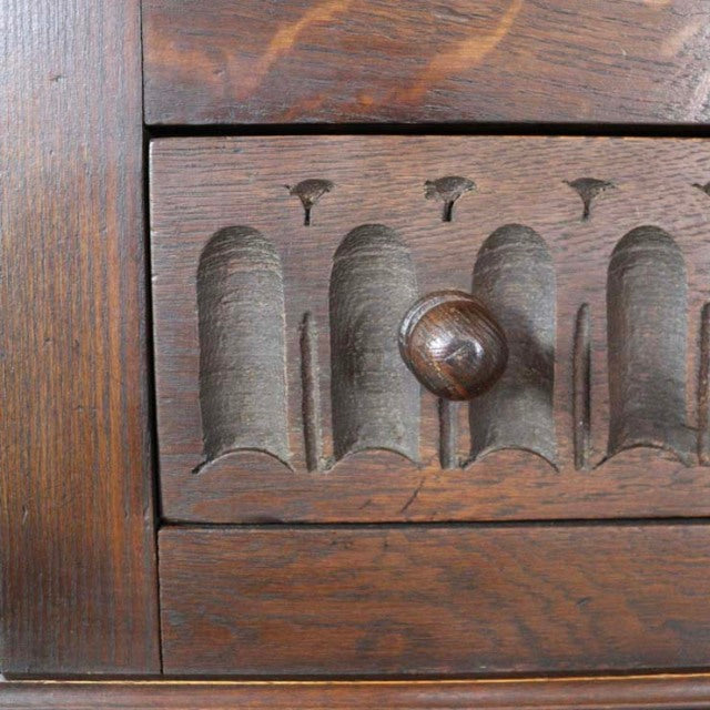 Close-up of British mid-century teak bedside cabinet drawer with carved arches and wooden knob, showcasing rich wood grain.