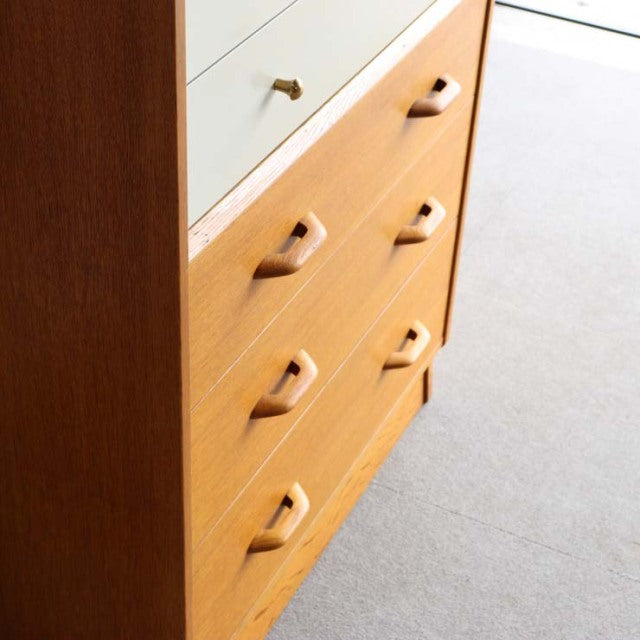 British mid-century G-Plan teak chest with warm wood grain, white top drawer, and tapered legs.