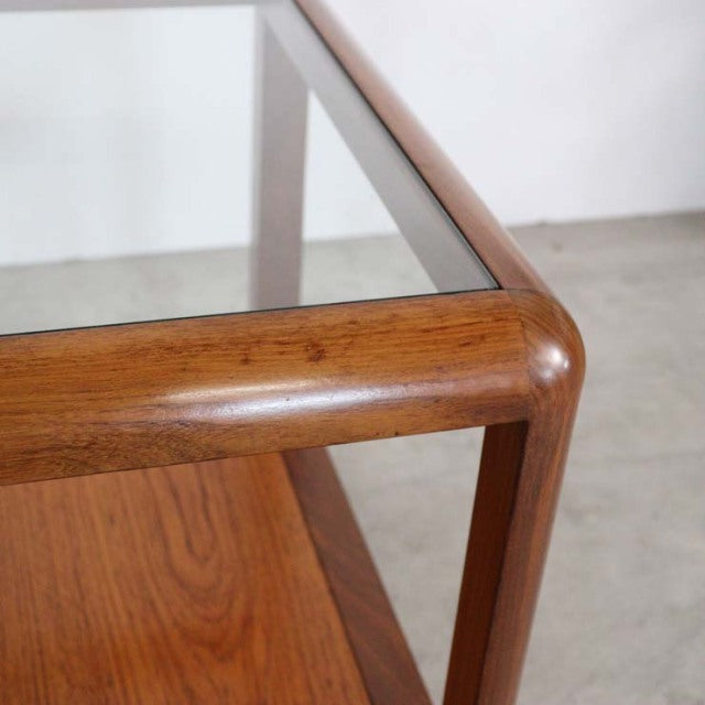 Mid-century British vintage teak coffee table with smooth rounded edges and glass top panel showing rich wood grain.