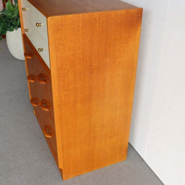 Mid-century British G-PLAN teak chest with smooth wood grain, rounded legs, and brass knobs in vintage Danish style.