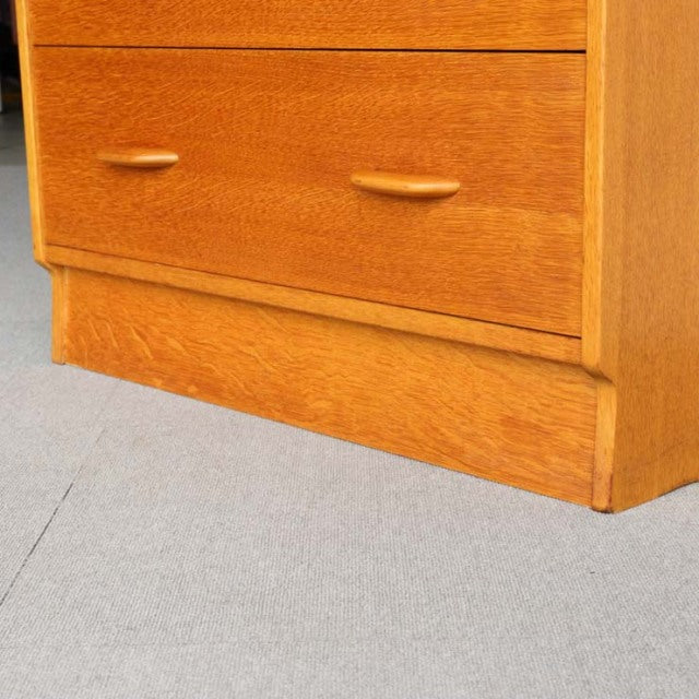 Mid-century British G-Plan teak chest with Chinese white accents, smooth wood grain, curved drawer handles, and tapered legs.