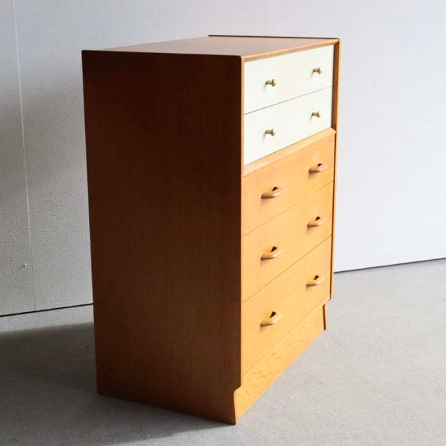 Vintage British mid-century G-Plan chest in teak with Chinese white drawer fronts and brass handles, showcasing clean lines.