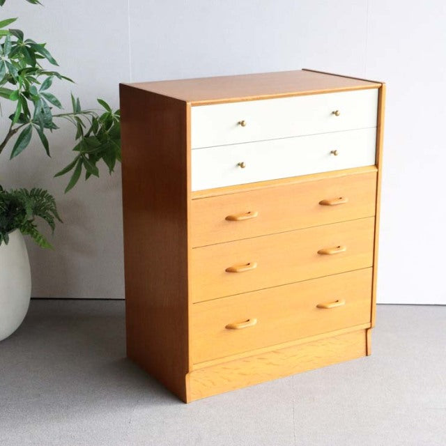 Vintage mid-century British G-Plan chest in teak with glossy Chinese white top drawers, wooden handles, and clean lines.