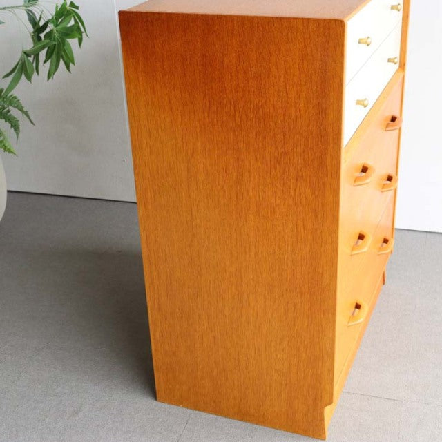 Vintage British mid-century teak chest with smooth grain, clean lines, and tapered legs visible from side angle.