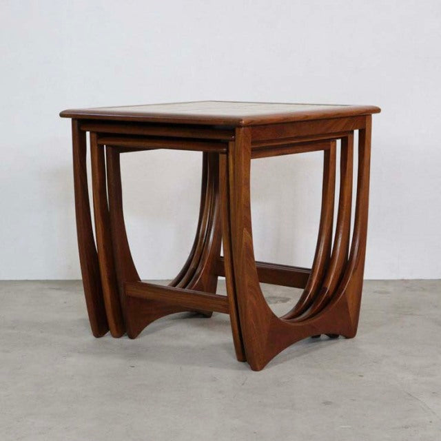 Vintage British mid-century teak G-Plan nest tables with curved legs and smooth wood grain finish.