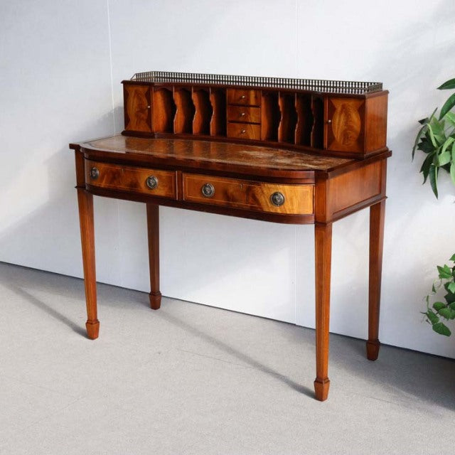 Vintage British teak mid-century desk with rich wood grain, slender tapered legs, and upper compartment with multiple small.