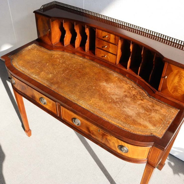 Vintage British mid-century teak desk with curved front, detailed wood grain, metal gallery rail, and tapered legs.
