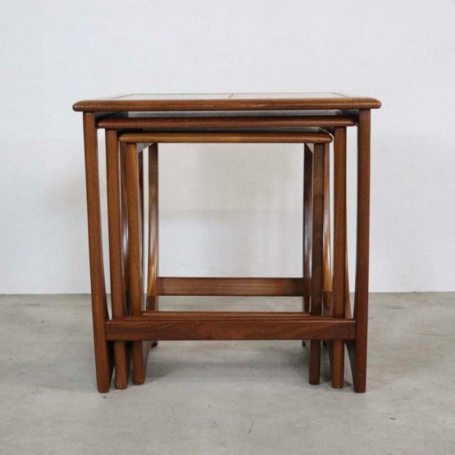 Set of three vintage British mid-century teak G-Plan nest tables with exposed wood grain and tapered legs.