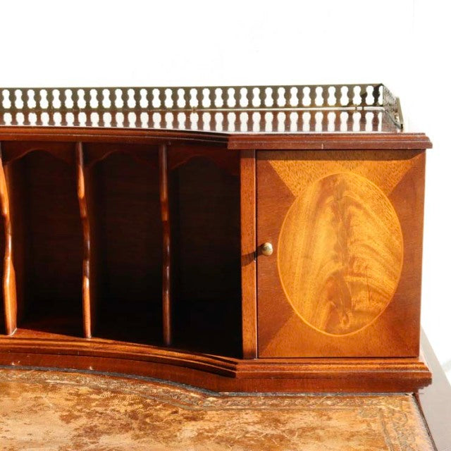 Vintage British mid-century teak desk with curved base, decorative brass gallery, and oval wood grain inlay on cabinet door.