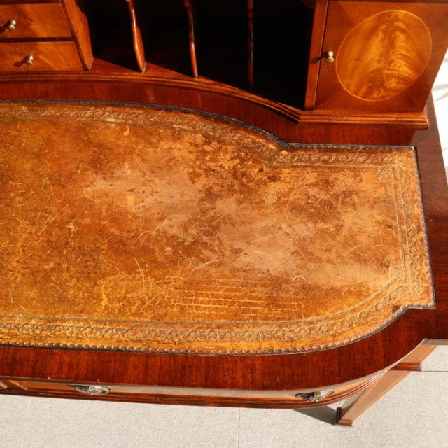 Vintage British mid-century teak desk with curved leather inset top, detailed wood grain, and rounded edges.