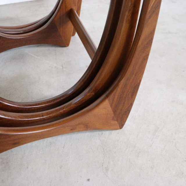 Close-up of vintage British mid-century teak nest table leg showcasing smooth curved grain and polished finish.