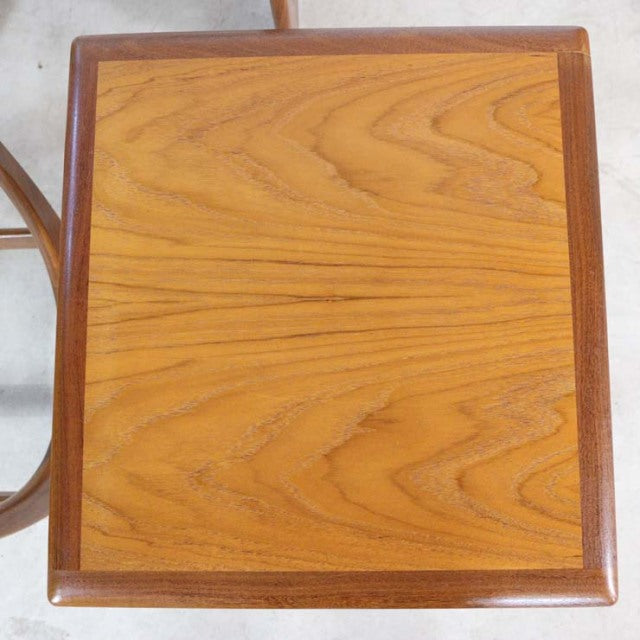 Vintage British mid-century teak nest table top with rich wood grain and rounded edges.