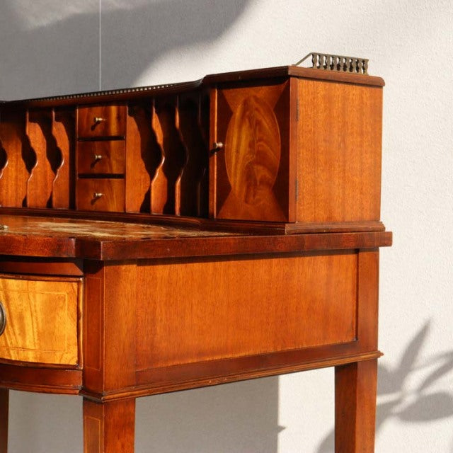 Mid-century British vintage teak desk with warm wood grain, slender legs, and upper compartments with curved front panels.