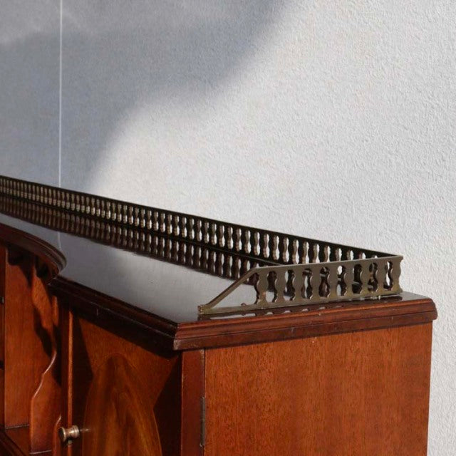Mid-century British vintage teak desk corner with rich wood grain and decorative brass gallery rail.