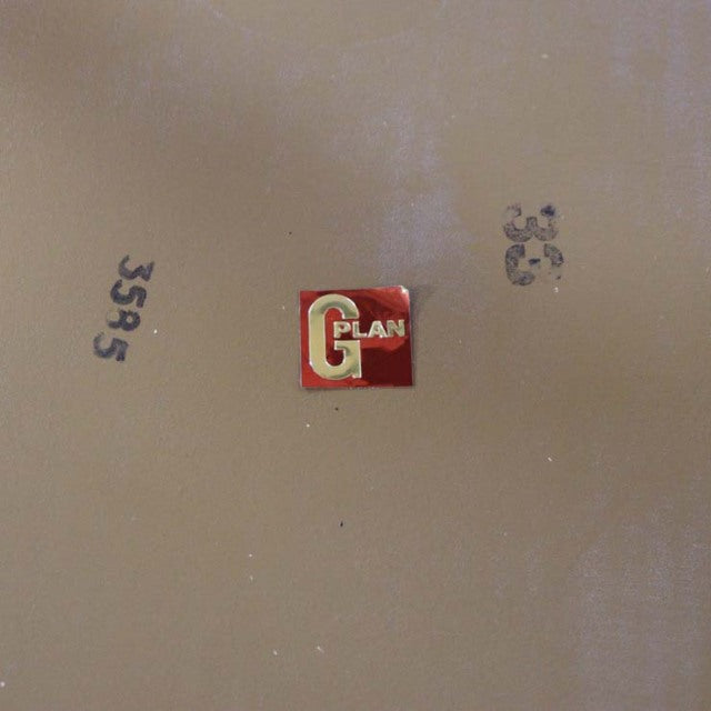 Red and white G-Plan logo badge on beige surface with black stamped numbers, reflecting vintage British mid-century branding.