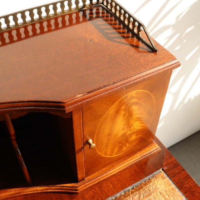 Vintage teak British mid-century desk with intricate wood grain and brass knob, elegant curved top edge, and detailed.