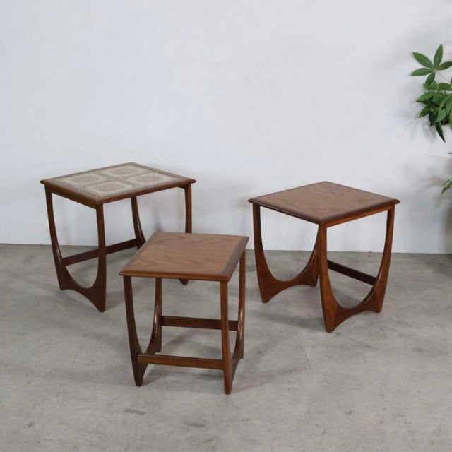 Set of three vintage G-Plan teak nest tables with mid-century British design, featuring smooth wood grain and tapered legs;.