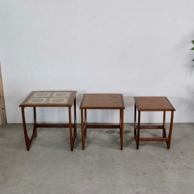 Set of three vintage teak G-Plan nest tables including one with decorative tile tops, British mid-century design, clean wood .