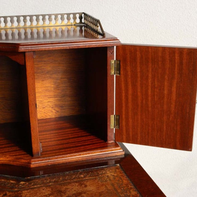 Vintage mid-century British teak desk cabinet door open showing rich wood grain and brass hinges.