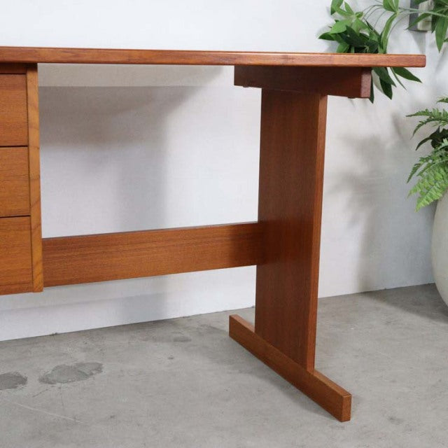 Mid-century vintage Danish teak desk with rich wood grain, T-shaped legs, and minimalist British-inspired design.